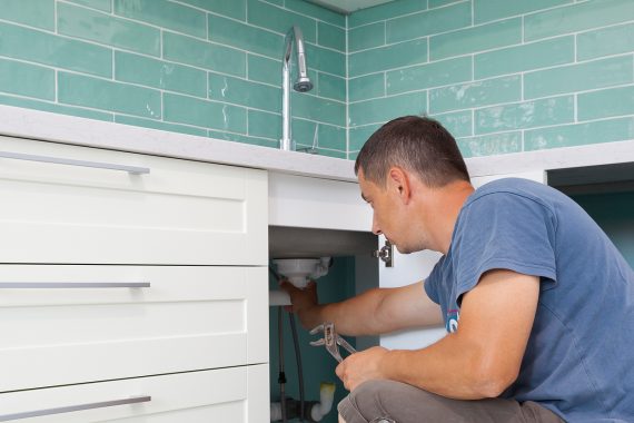 Professional plumber in Wellington repairing the kitchen sink